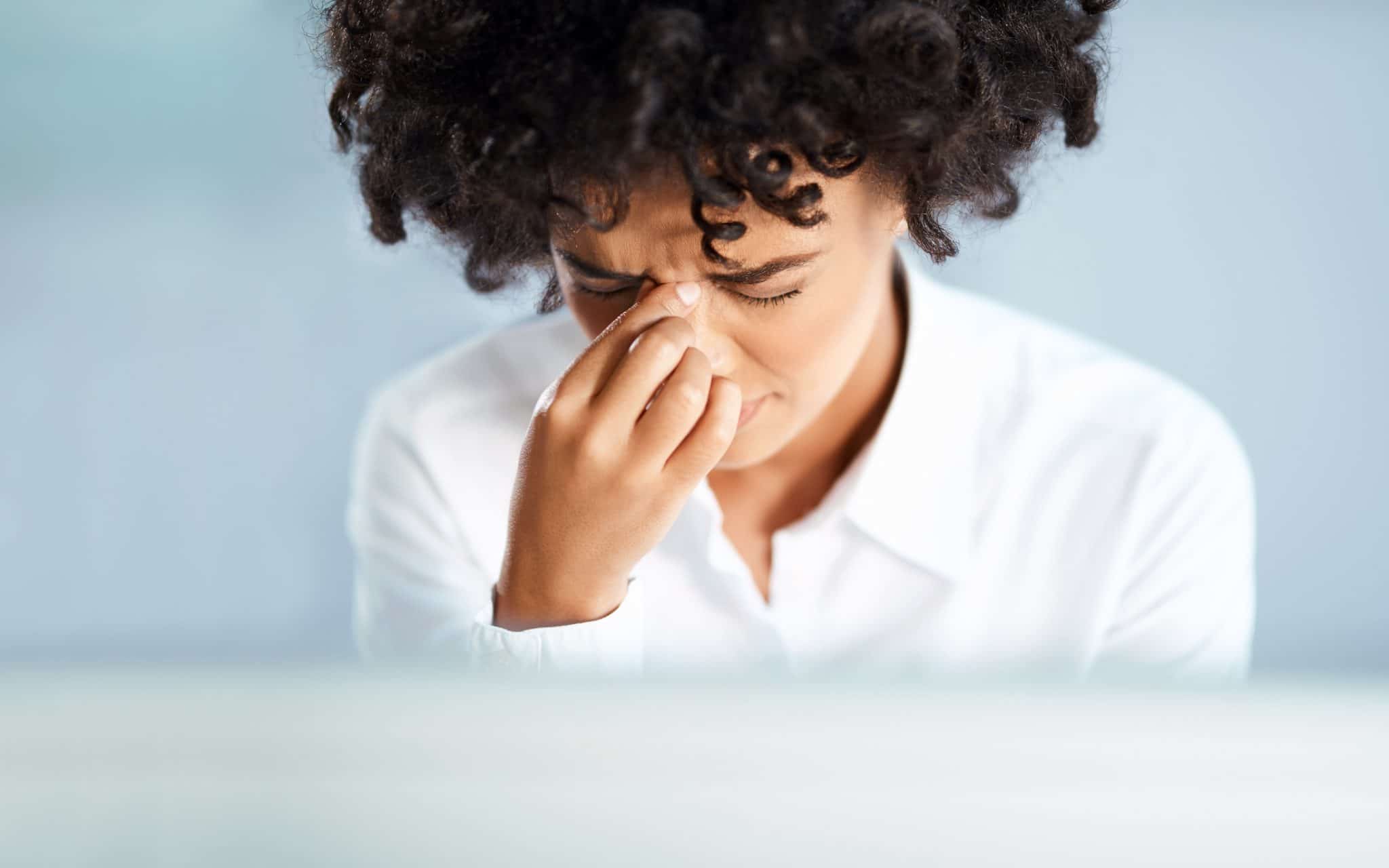 Shot of a young businesswoman looking stressed out because of sinus pressure.