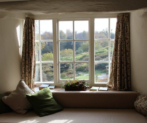 A couch next to a window inside of a home.