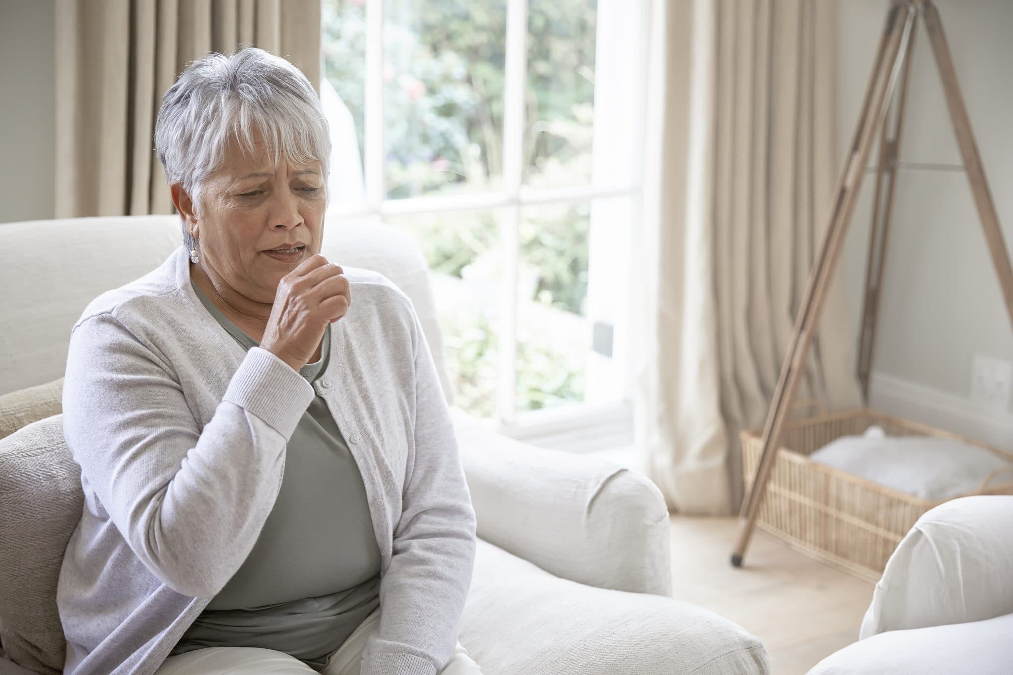 Woman coughing in her living room at home.