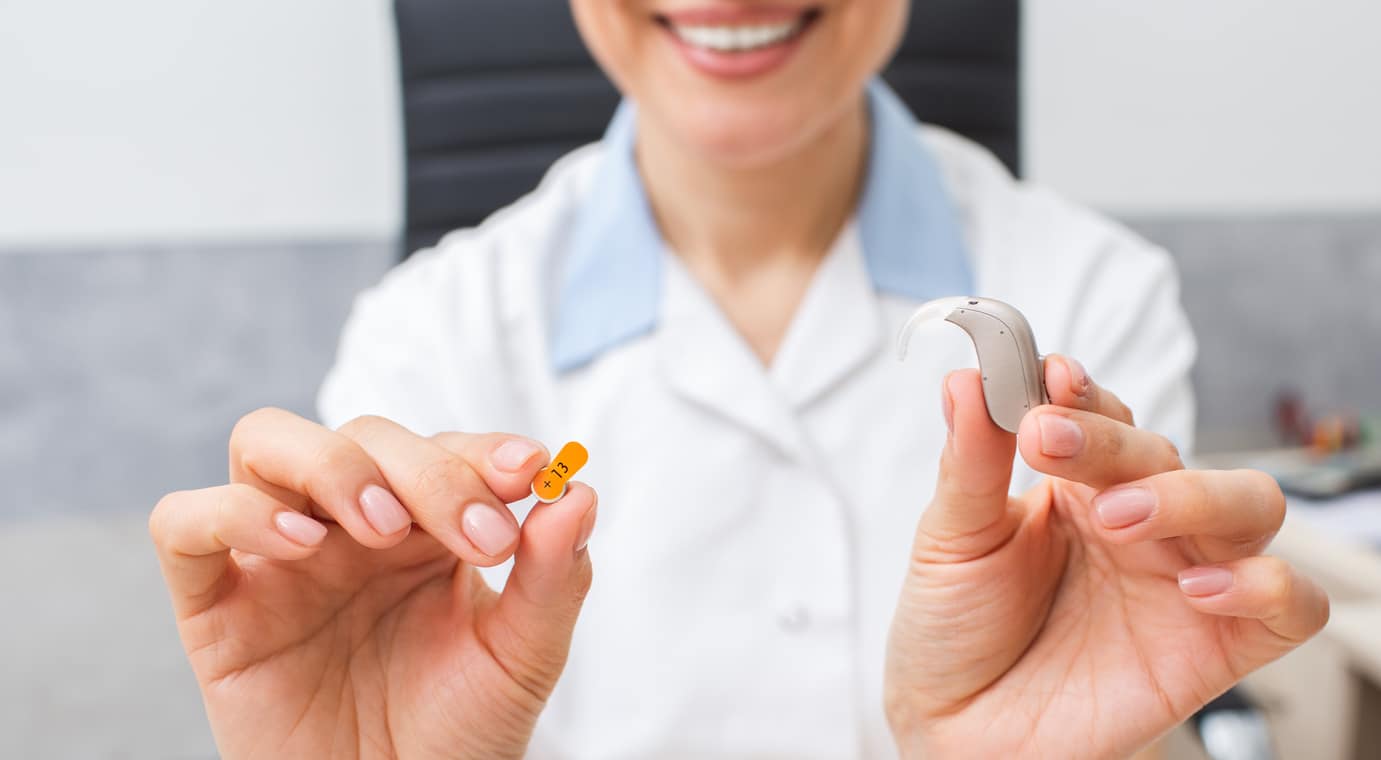 Audiologist holding a hearing aid in her hand.