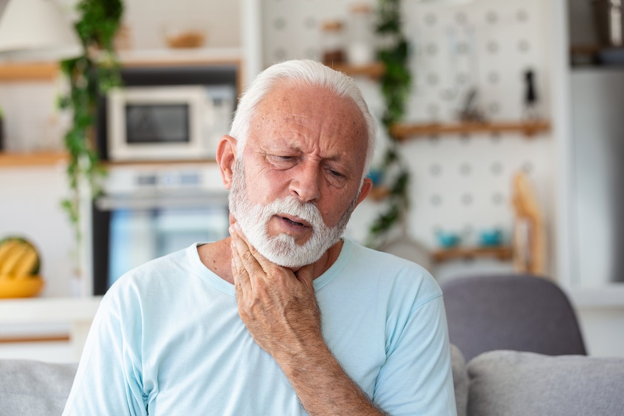 Man who lost his voice holds his throat.